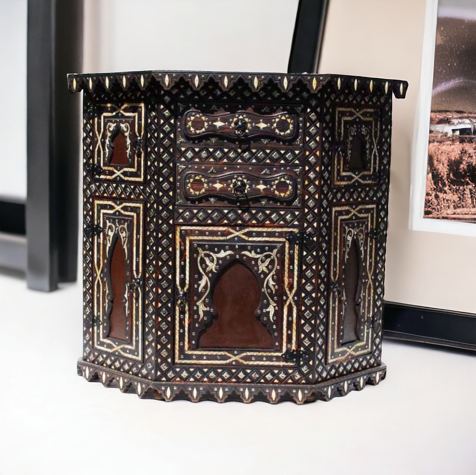 A unique inlaid white camel bone cabinet with storage space, featuring door panels and drawers, positioned against a background of home decor items.