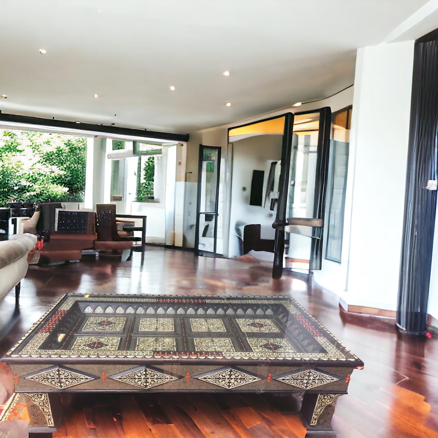 A large rectangular camel bone inlaid table with metal accents, placed on a hardwood floor within a room with high ceilings and large windows.