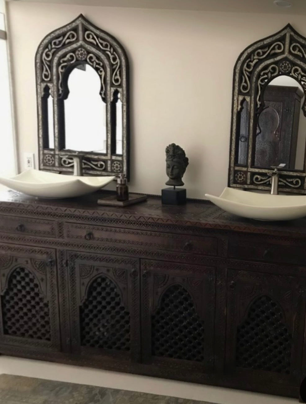 Two ornate mirrors on a dark wooden vanity Moroccan cabinet.