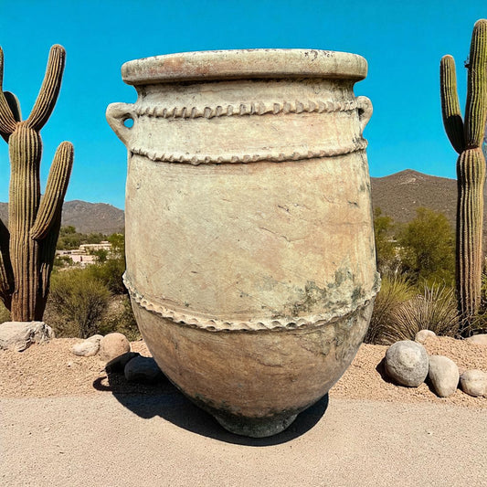 Large ceramic pot in a desert setting with cacti and clear blue sky