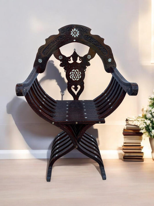 A vintage ottoman scissors chair with hand-carved wooden frame and white mother of pearl shell inlays, featuring two crossed and curved supports.